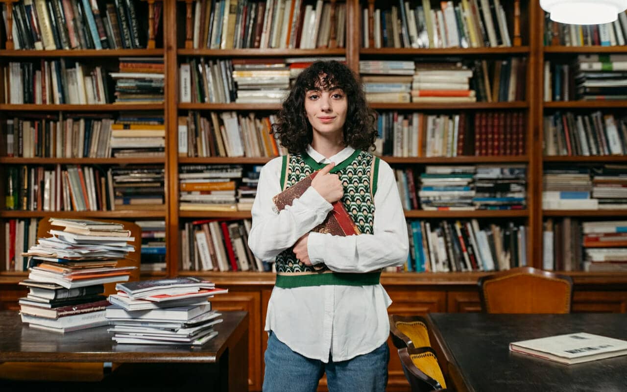 a woman is holding a book in front of a book shelf