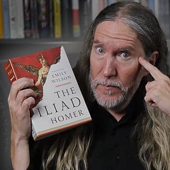 Anthony Metivier holding a copy of the Iliad while pointing at his head to illustrate memorization in this feature image for how to remember a story