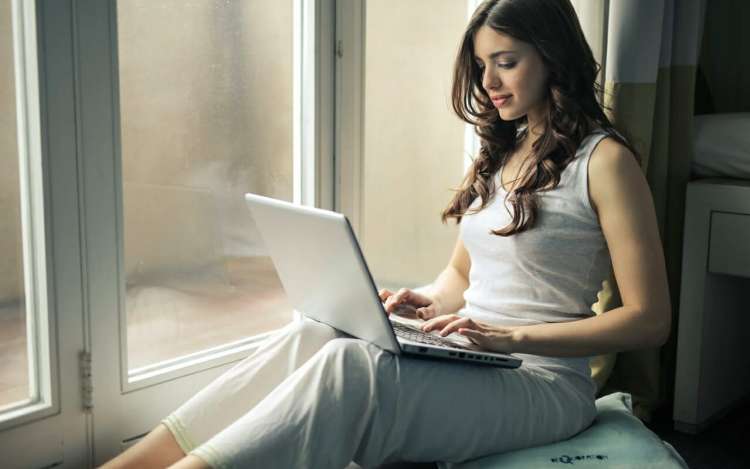 a woman using her laptop beside a window