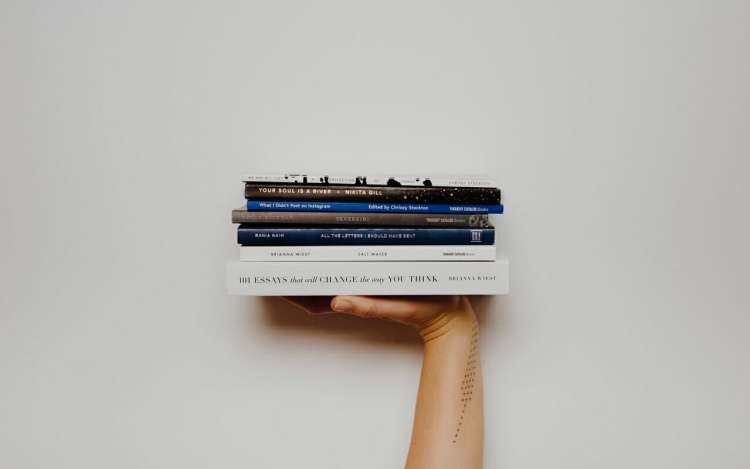 a hand is holding pile of books