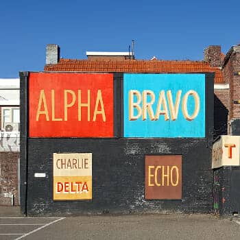 Alphabet Mnemonics feature image with military phonetic alphabet displayed on the side of a building