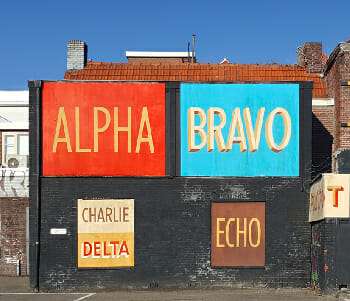 Alphabet Mnemonics feature image with military phonetic alphabet displayed on the side of a building