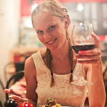 how hard is it to learn italian feature image of a woman enjoying an italian meal with italian wine