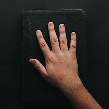 image of a hand on the bible feature image for is it possible to memorize the bible