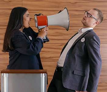 Feature image for how to prepare for a debate of a woman yelling at a man with a megaphone