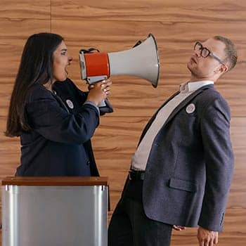 Feature image for how to prepare for a debate of a woman yelling at a man with a megaphone