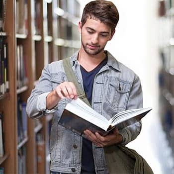 study habits feature image of a young man with a book in a library