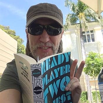 how to become an autodidact feature image with Anthony Metivier holding a copy of Ready Player Two